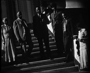 Kadras iš kino filmo. Prie M. Sleževičiaus namo. Iš kairės: O. Pavalkienė, M. Sleževičius, K. Sleževičius, P. Cvirka, M. Mackevičius, M. Sleževičiūtė- Mackevičienė. 1934 m.