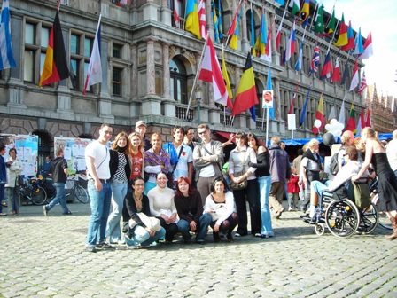 Aikštėje netoli miesto  Merijos dalis „Erasmus“ studentų stovi prie savo šalių vėliavų