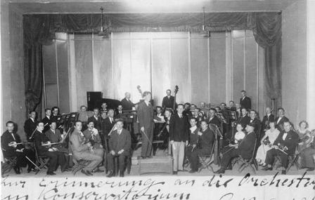 Muzikos mokyklos orkestro repeticija Šaulių namų salėje. 1933 m. birželio 22 d. Viduryje iš kairės sėdi mokyklos direktorius Ignas Prielgauskas, stovi dirigentas Jeronimas Kačinskas ir dainininkas Stepas Sodeika. Nuotraukoje vokiečių kalba užrašyta J. Kačinsko dedikacija dainininkui Ernstui Schumannui (p. 304)